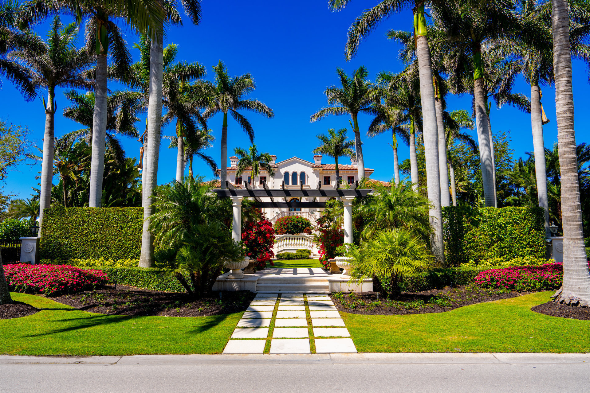 Luxury Florida mansion with tropical landscaping under blue sky